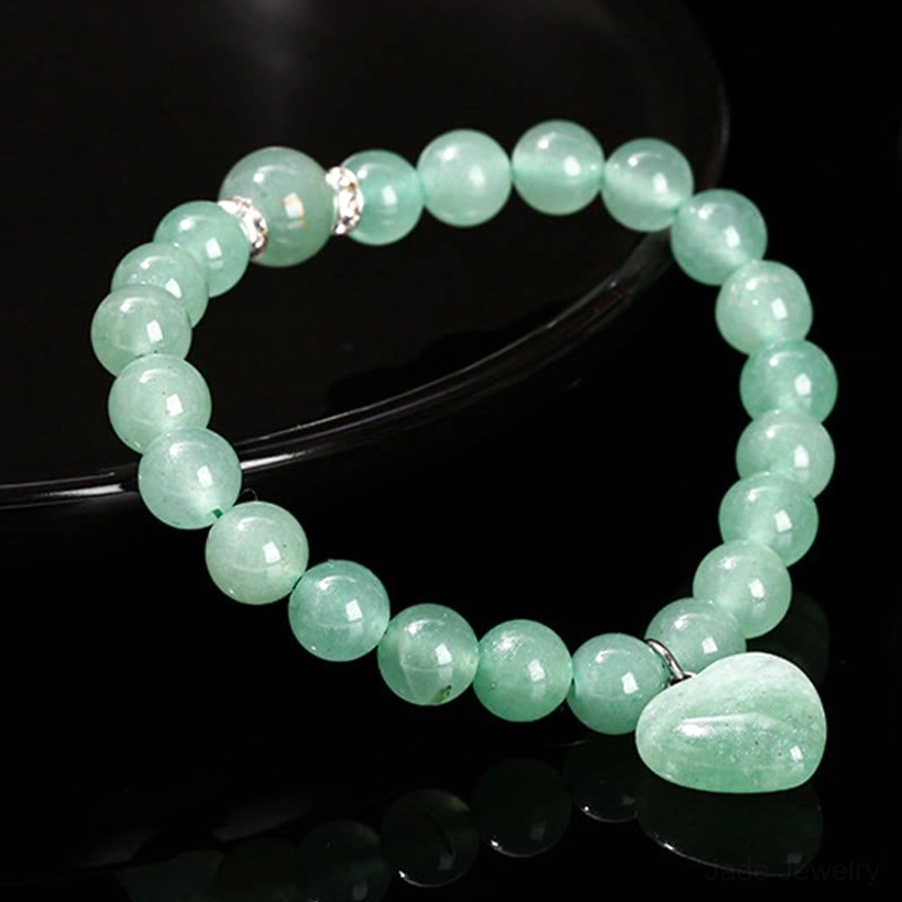 Light green aventurine beaded bracelet with heart pendant and metal rhinestone spacers on black reflective surface