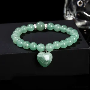 Green Aventurine heart charm bracelet with metal spacer beads on black display platform