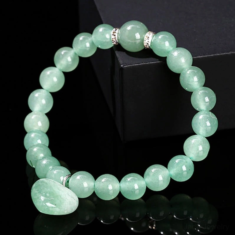 Natural green aventurine stone heart charm bracelet on black display stand with reflective background