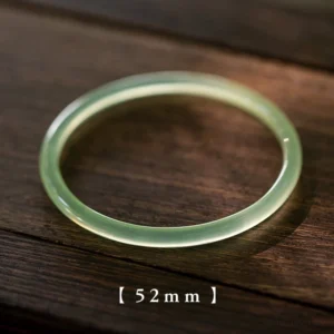 Single natural green chalcedony bangle 52mm inner diameter, polished glossy finish, flat lay on dark wood