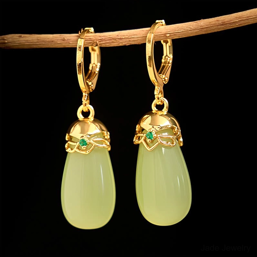Green chalcedony jade earrings hanging on wooden branch with floral metal cap details and small green stone accents minimalist styling