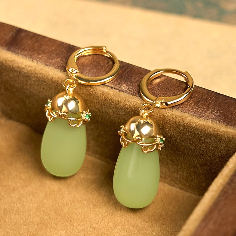 Green chalcedony water drop earrings in wooden jewelry storage tray oblique view polished gold metal with pale green jade drops