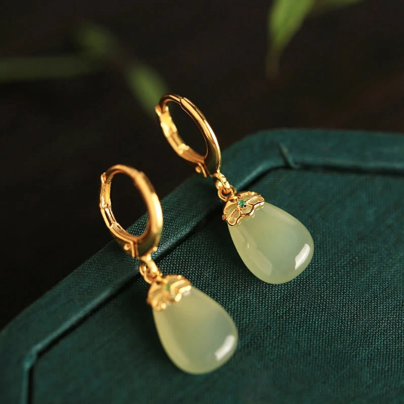 Green chalcedony water drop earrings side top view on dark green velvet surface light green jade drop polished gold earring simple metal cap