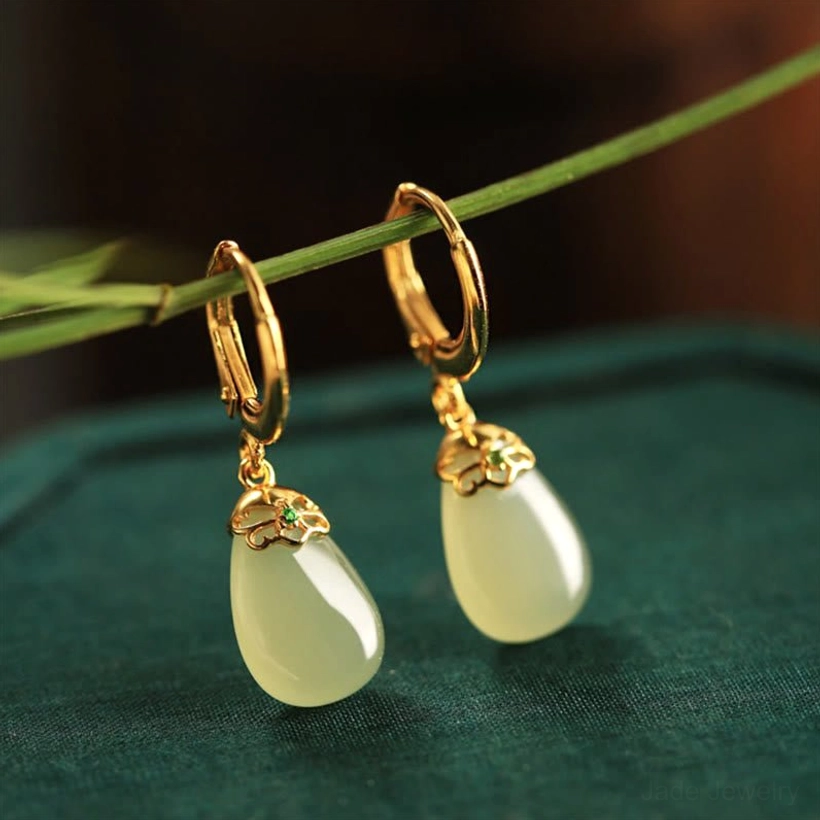 Green chalcedony jade water drop earrings on dark green velvet background with grass stem pale green jade gold ear hook small gem decoration