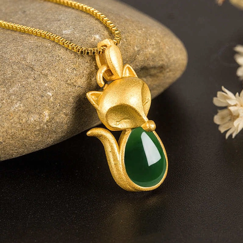 Green chalcedony fox gold necklace pendant with teardrop jade inlay - side view on dark table with stones and dried flowers