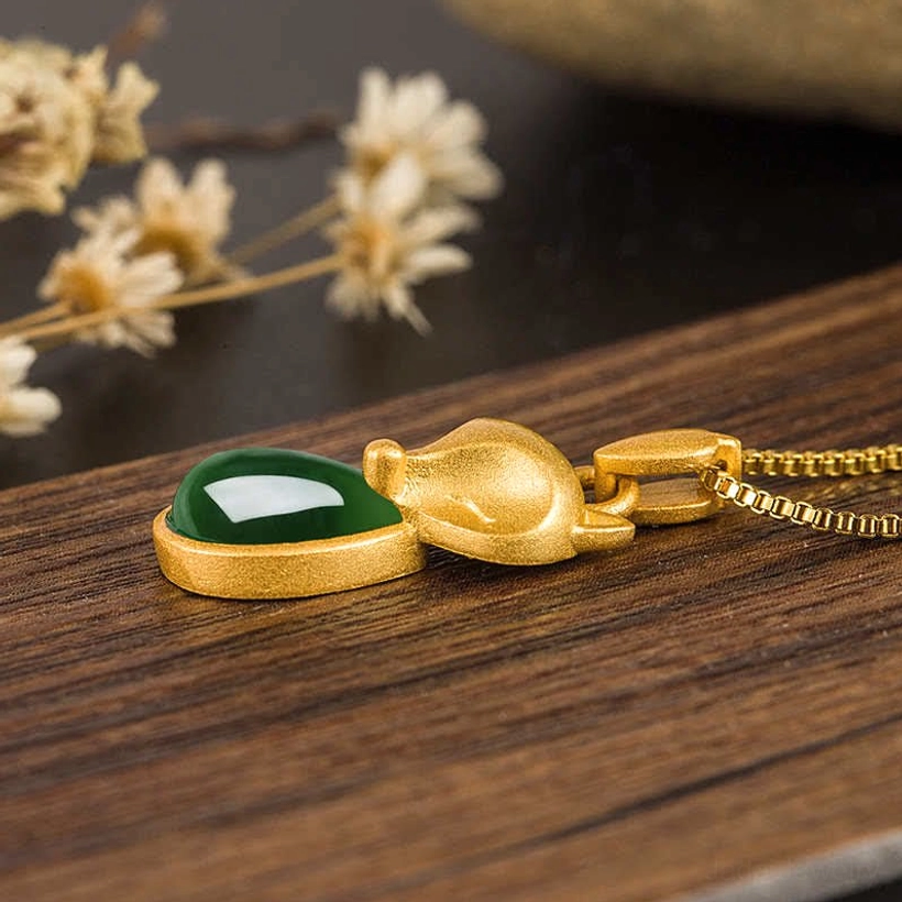 Gold fox pendant with green chalcedony - top-down flat lay on wooden surface showing side profile