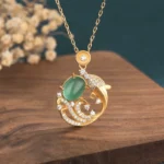 Green chalcedony koi fish pendant necklace front view with gold copper setting and zircon accents on wooden coaster
