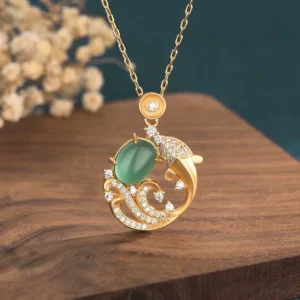 Green chalcedony koi fish pendant necklace front view with gold copper setting and zircon accents on wooden coaster