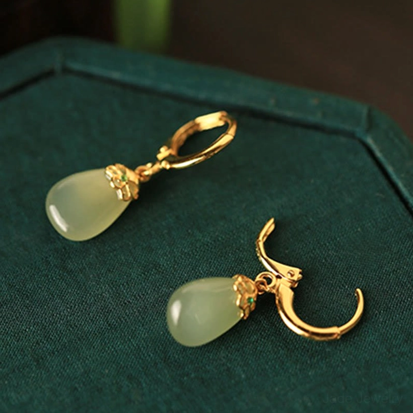 Single green chalcedony jade drop earring two display angles oblique top view dark green velvet background pale green stone gold ear hook