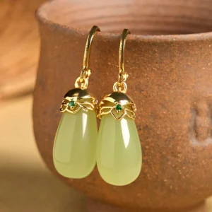 Green chalcedony water drop earrings with copper posts front view on terracotta pottery background showing pale green jade stones with gold-toned metal accents
