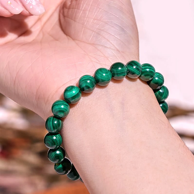 Green harmony balance bracelet, overhead view on warm background showing complete beaded design and elastic construction