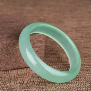 Single natural green jade bangle bracelet side view showing smooth polished glossy finish