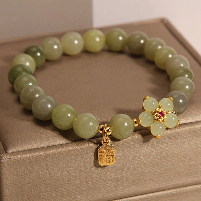Close-up of jade beads showing smooth polished surface, light green coloration, and elastic band construction