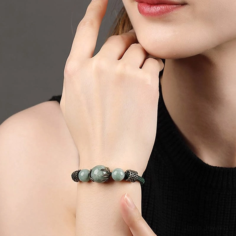 Green jade bracelet worn on delicate wrist showing slim fit and vintage bronze ornamentation