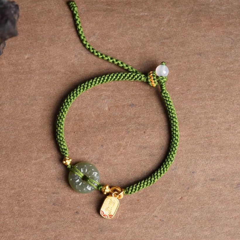 Top-down view of green jade peace buckle bracelet on wooden background