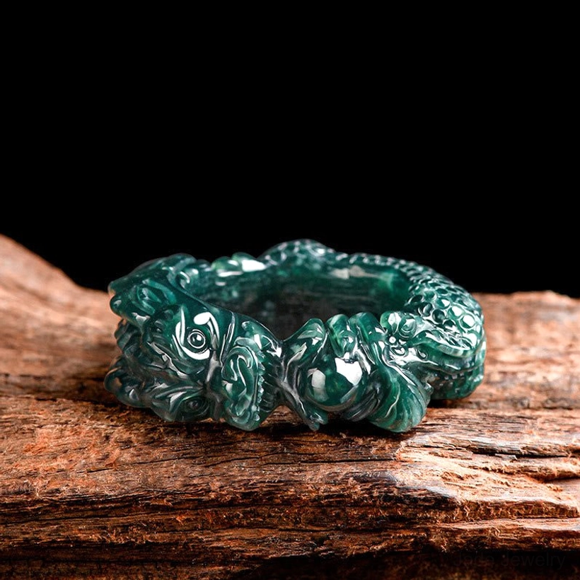 Top-down front view of cyan jade dragon ring showing double dragon head design and intricate carved texture in dark green jade