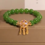 Green jade dreamcatcher four leaf clover luck bracelet with gold charm - side view on jewelry box