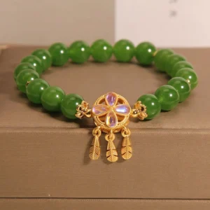 Green jade dreamcatcher four leaf clover luck bracelet with gold charm - side view on jewelry box