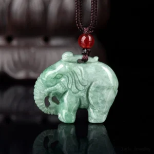 Natural green jade elephant pendant necklace with intricate hand-carved details, traditional brown waxed cord and red glass accent bead, displayed on dark reflective surface