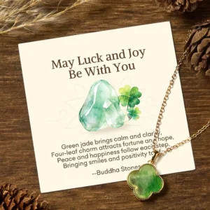 Green jade four-leaf clover luck necklace with personalized blessing message card, gold-plated pendant, and delicate chain displayed on wooden table with natural pinecones