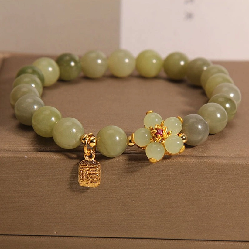 Green jade Fu character bracelet in brown gift box - overhead flat lay showing gradient jade beads, gold flower charm, and metal Fu pendant