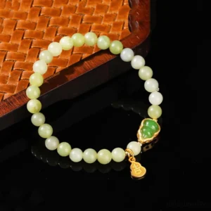 Green jade beaded lucky bracelet with gold Fu character charm and jade gourd pendant on woven wooden coaster