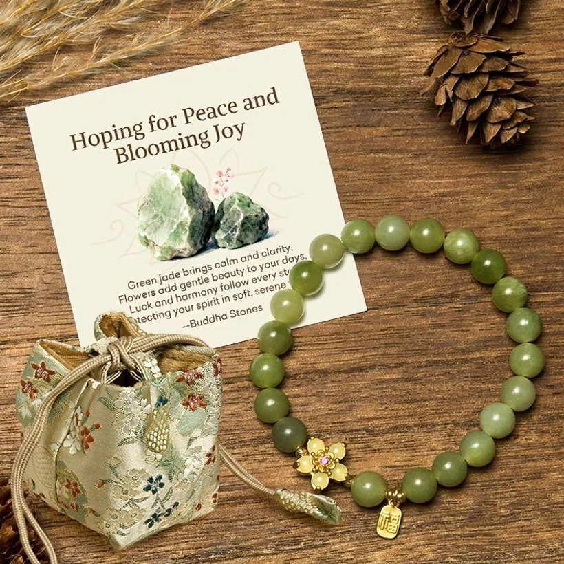 Green jade bracelet with complementary embroidered gift bag and message card arranged on wooden table with natural decor elements