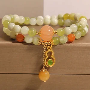Green serpentine jade double wrap bracelet with carved gourd charm, flat lay display on brown jewelry box