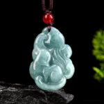Natural light green jade nine-tailed fox pendant necklace with red bead and brown cord, front view on stone base