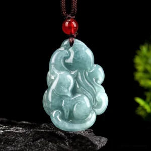 Natural light green jade nine-tailed fox pendant necklace with red bead and brown cord, front view on stone base