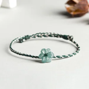 Dark green and light gray braided jade orchid prosperity bracelet with adjustable knot, displayed on minimalist light background