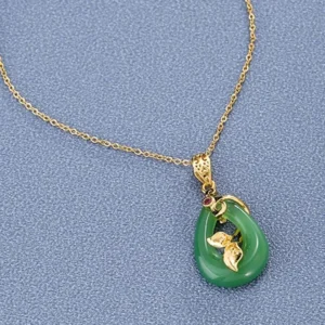 Green jade teardrop pendant necklace with delicate gold chain and ornate floral gold leaf design detail shot - luxury handcrafted jade jewelry