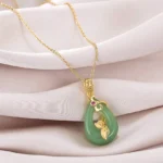 Green jade oval pendant necklace with gold chain, gold leaf ornament and red gemstone accent on pink satin - handmade prosperity charm