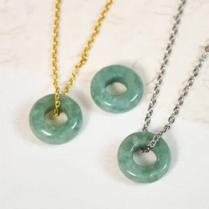 Green jade peace buckle necklaces in gold and silver - flat lay overhead desktop view showing authentic natural jade pendants with detailed stone texture