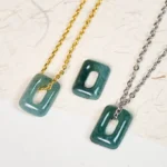 Matching green jade square pendant necklaces with gold and silver chains, flat lay overhead view on textured background