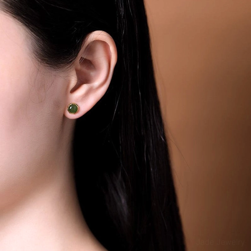 Woman wearing dark green jade stud earring with gold bezel on earlobe, demonstrating elegant wearing effect and side profile