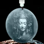 Guanyin Avalokitesvara jade pendant front view showing intricately engraved Bodhisattva face on natural dark teal jade