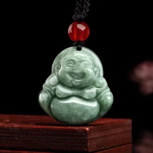 Direct frontal close-up of hand-carved jade Buddha pendant showing intricate smiling facial features, smooth polished finish, and top suspension hole