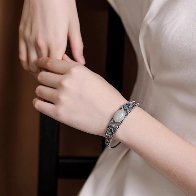 Handcrafted jade bangle bracelet detail shot, showcasing fine filigree work, floral motifs, and premium finish