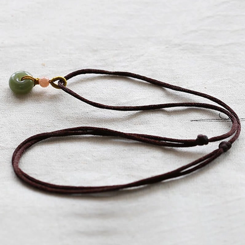 Handcrafted jade peace buckle pendant with natural stone variations, artisan detail