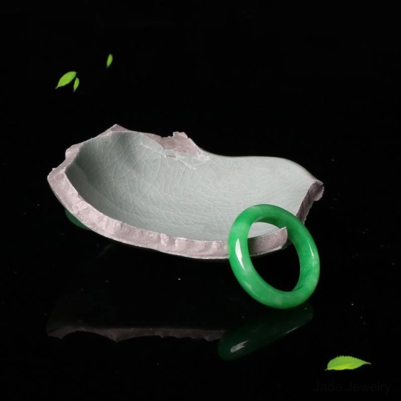 Single green jade prosperity ring minimalist band three quarter view black backdrop