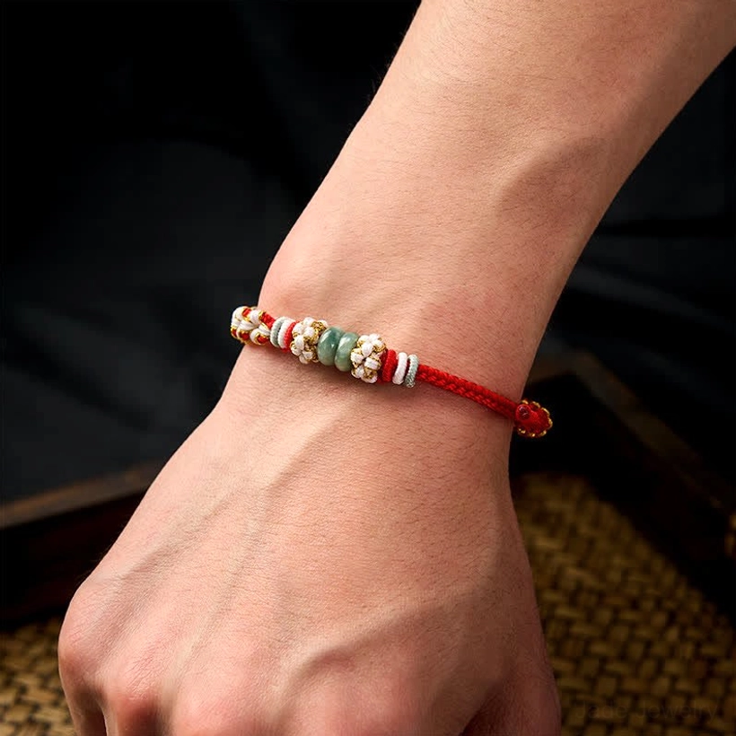 Handmade jade red string wearable luck bracelet close-up on wrist