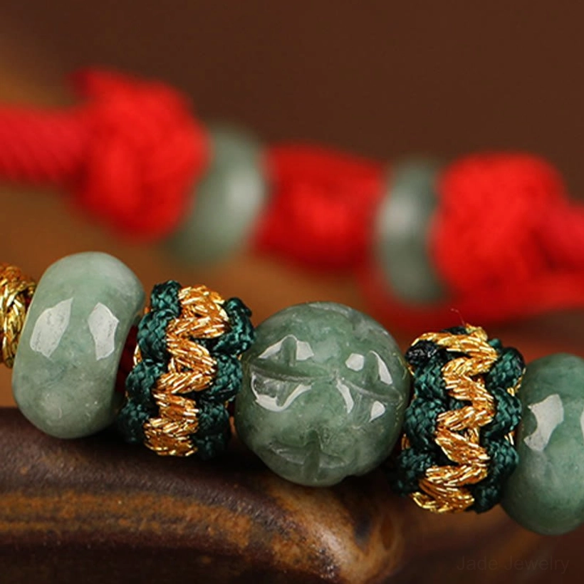 Handcrafted jade prosperity bracelet showing woven red string pattern and gold thread embellishment close-up