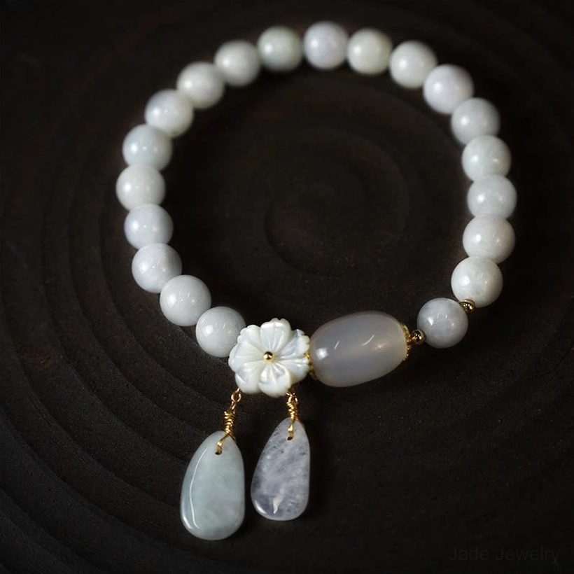 Handmade white jade purity bracelet with delicate flower charm demonstrating traditional jade craftsmanship