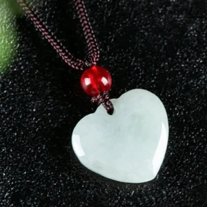 Close-up three-quarter angle of natural green jade heart pendant showing polished surface and woven rope detail