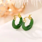Hetian cyan jade drop earrings with gold-plated sterling silver lever-back clasp, top-down flat lay view on satin fabric