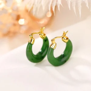 Hetian cyan jade drop earrings with gold-plated sterling silver lever-back clasp, top-down flat lay view on satin fabric
