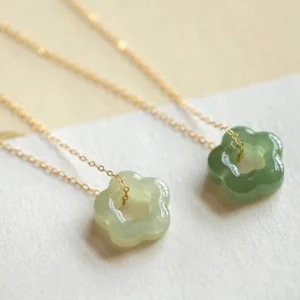 Hetian cyan jade flower pendant necklace with dual green jade tones hollow five-petal design thin gold chain flat lay