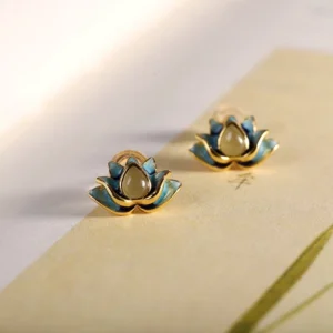 Hetian cyan jade lotus stud earrings flat lay with vintage paper background, showing gold-toned sterling silver and natural jade stone detail