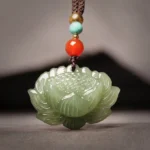 Hetian cyan jade lotus flower pendant necklace with red agate accents on brown cord, front overhead close-up view